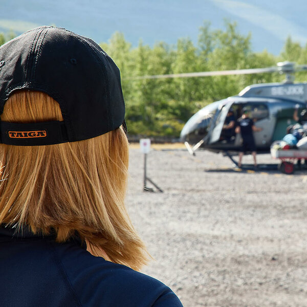 Woman wearing a Taiga cap next to a helicopter