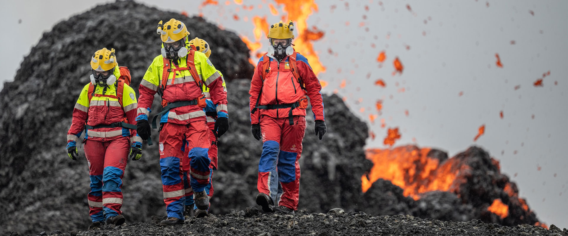 Search & Rescue personnel wearing Taiga workwear in front of an active volcano